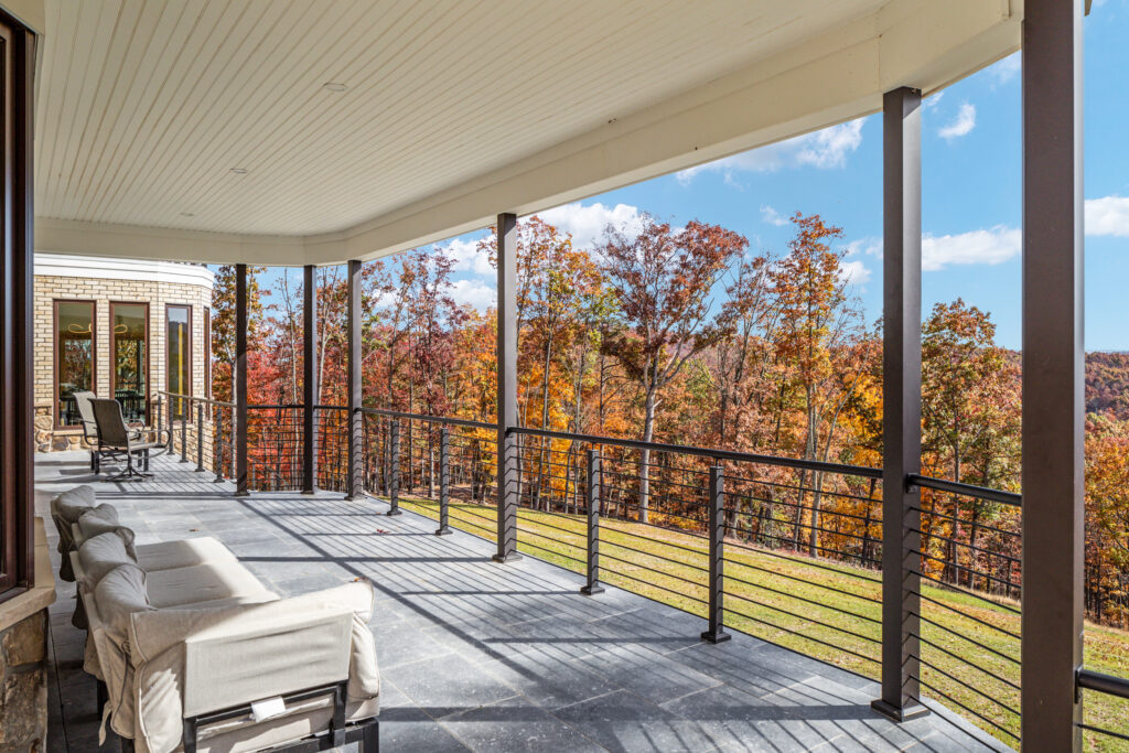 Large covered deck with lounge seating and mountain forest views at The Vale luxury cabin in Lost River West Virginia