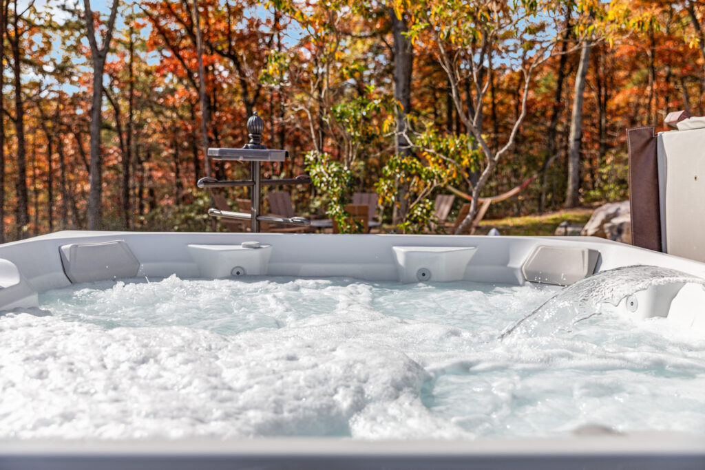 Outdoor hot tub surrounded by forest views at The Vale luxury cabin in Lost River West Virginia