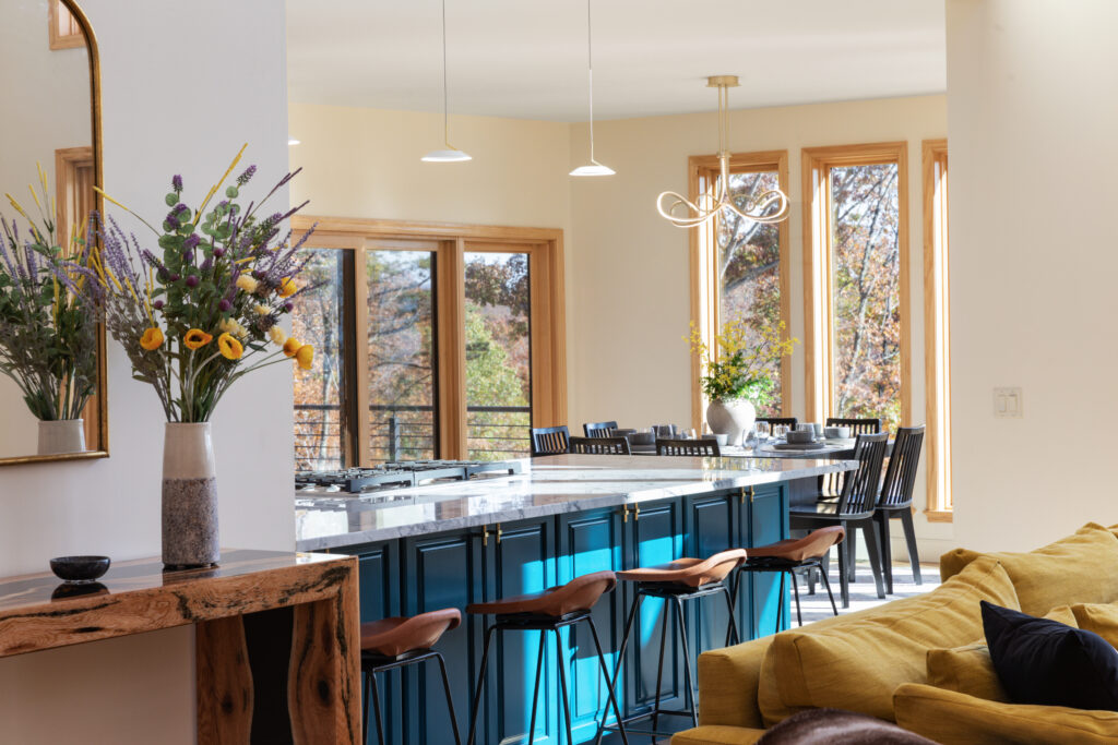 Kitchen island and dinning room with floor to ceiling windows and plenty of natural light at the luxury cabin in Lost River, West Virginia