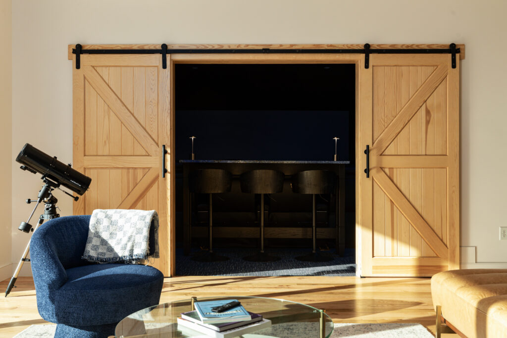 Downstairs living room with telescope and barn doors leading to the movie theater at The Vale luxury cabin in Lost River West Virginia
