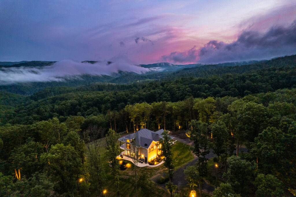 Aerial view of The Vale luxury cabin surrounded by forest and mountains at dusk in Lost River West Virginia