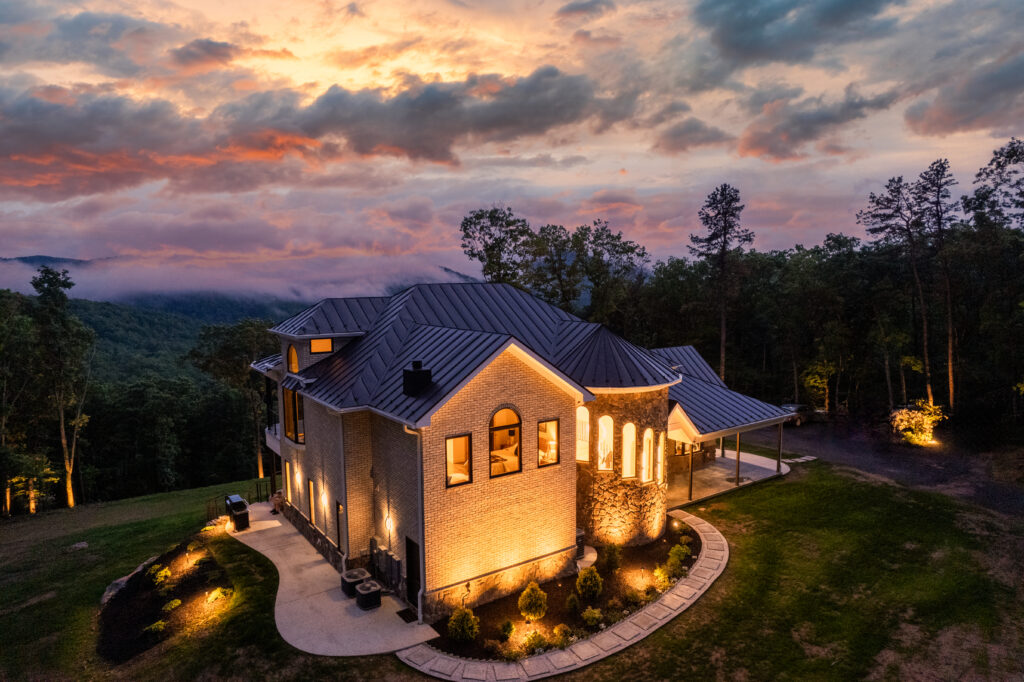 Luxury mountain cabin at sunset with exterior lighting at The Vale in Lost River Estates West Virginia