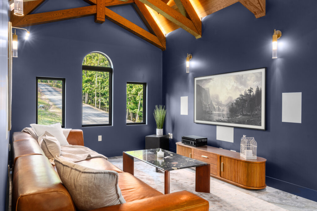 Media room with vaulted beam ceiling and forest-view windows at The Nook