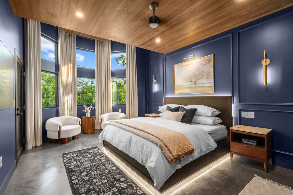 Guest bedroom with navy accent wall, wood-plank ceiling, and plush king bed at The Nook