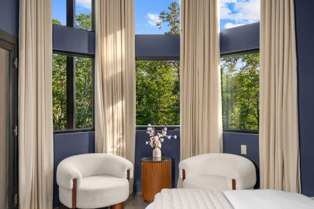 Bright sitting area with floor-to-ceiling windows and accent chair at The Nook luxury cabin