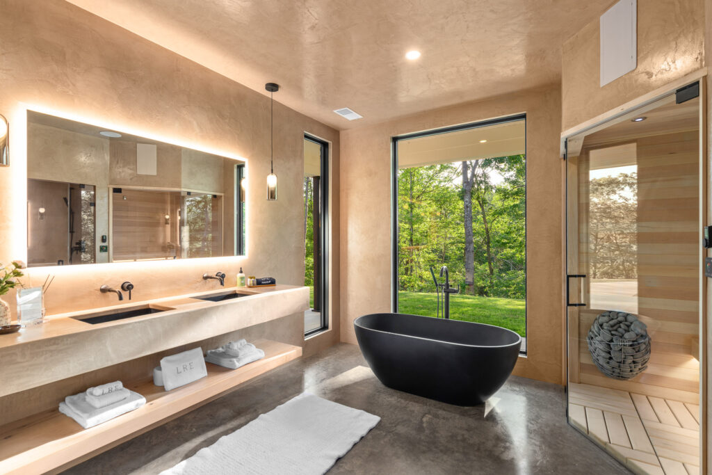 Freestanding tub with forest views through floor-to-ceiling windows at The Nook