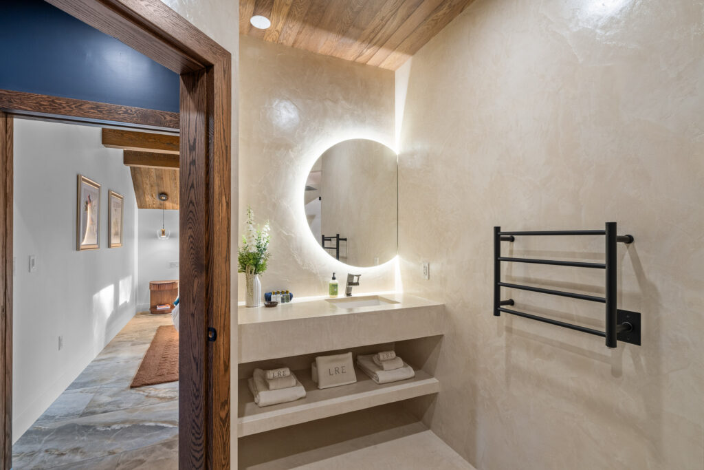 Modern bathroom with backlit round mirror and floating vanity at The Nook