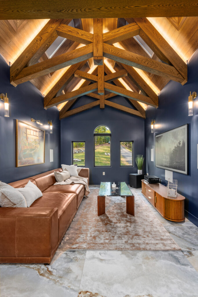 Loft media room with vaulted exposed-beam ceiling and leather sofa at The Nook