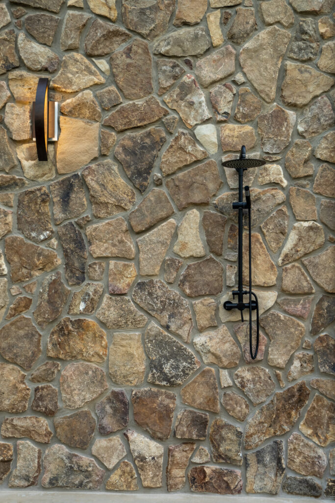 Outdoor shower set into a natural stone exterior wall at The Nook