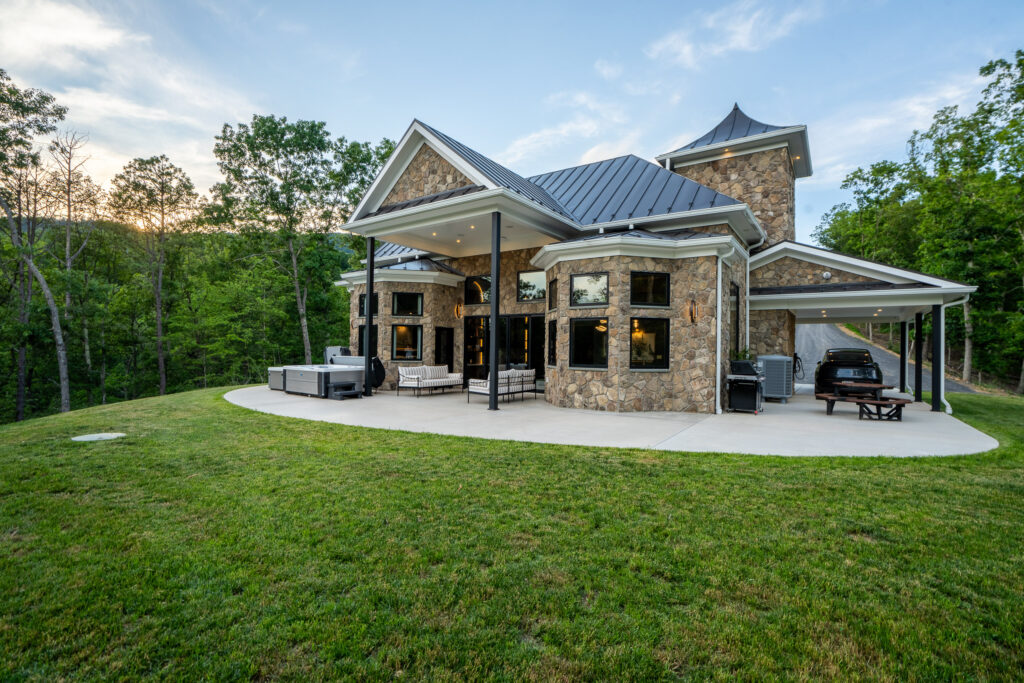 Daytime exterior of The Nook luxury cabin with stone-and-wood facade and green lawn