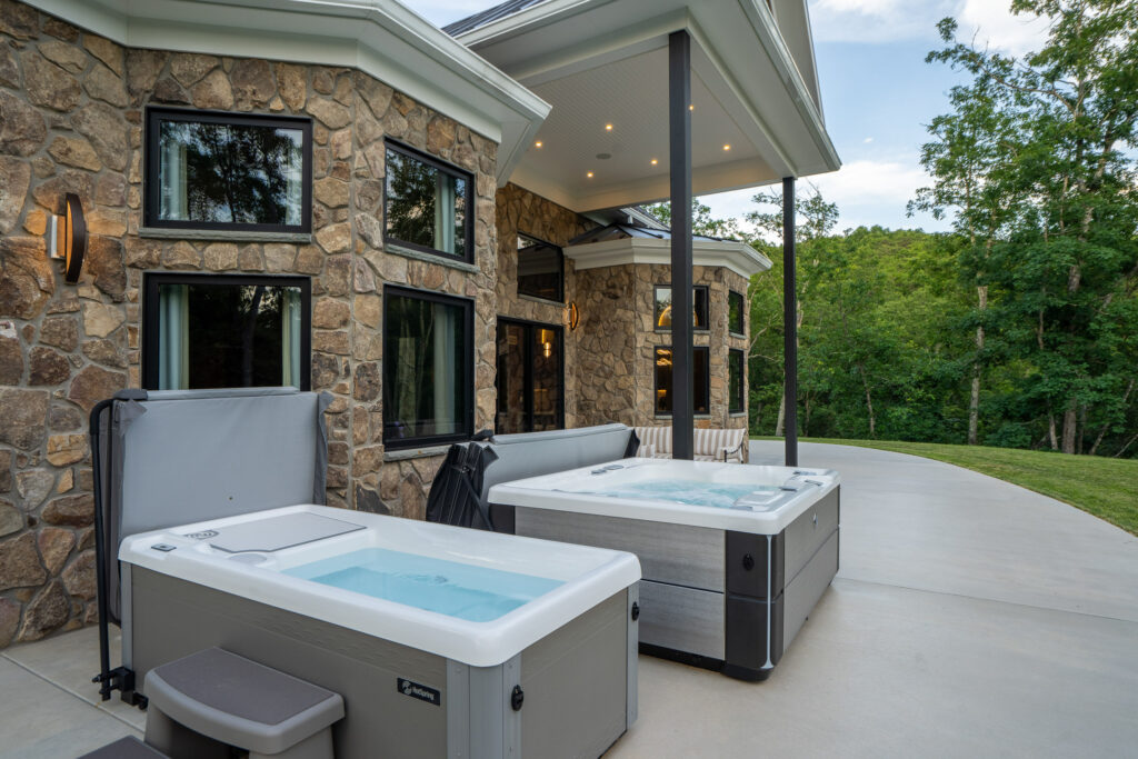 Spa bathroom with hot tub, cold plunge and stone accent wall beside large windows at The Nook