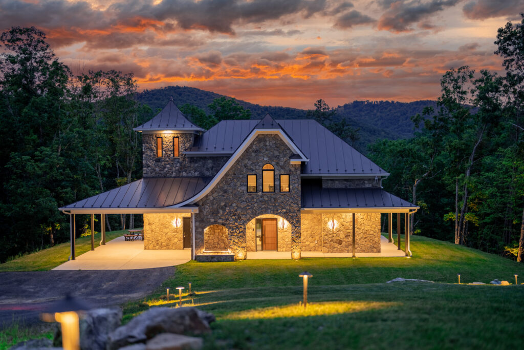 Aerial twilight view of The Nook luxury cabin glowing among forested mountains in Lost River, West Virginia